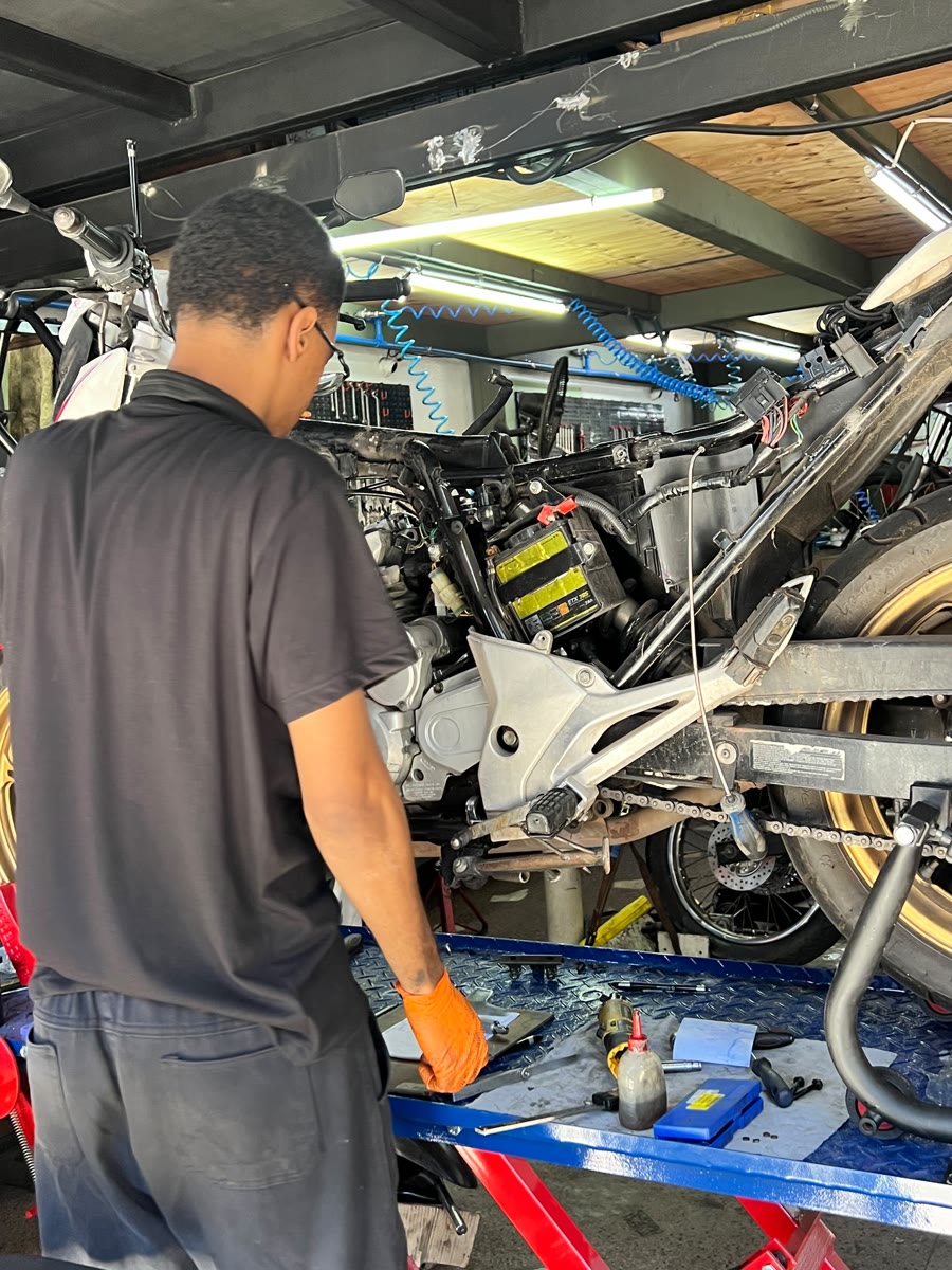 Mecânico da Tiradentes na bancada, com a moto desmontada no elevador