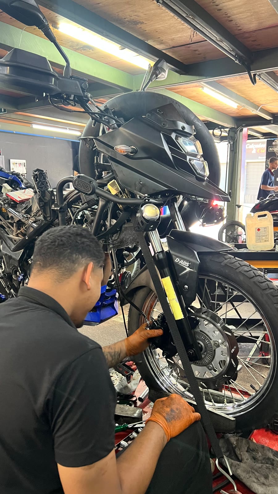 Mecânico da Tiradentes trabalhando na suspensão dianteira de uma moto